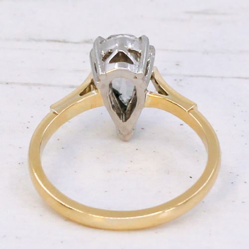 A vintage solitaire ring featuring a pear-cut diamond held in white metal claw settings on a smooth yellow gold band. View V