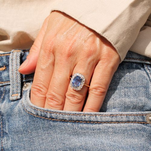 fig 1. A cushion-cut blue Ceylon sapphire set in a multi-claw setting surrounded by a halo of brilliant white diamonds on a yellow gold band.