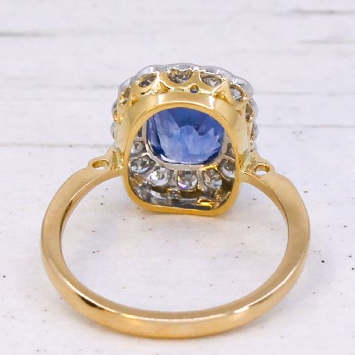 fig 4. A cushion-cut blue Ceylon sapphire set in a multi-claw setting surrounded by a halo of brilliant white diamonds on a yellow gold band.