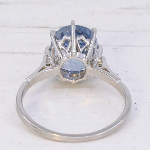 An Art Deco platinum solitaire ring featuring a large oval-cut light blue sapphire held in an eight-claw setting. View V