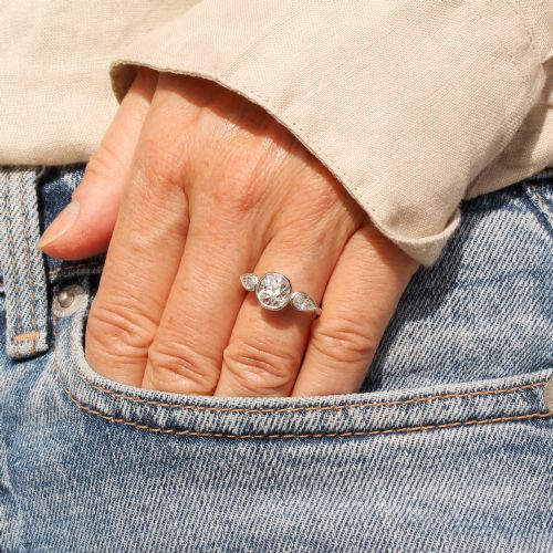 fig 1. An Art Deco platinum ring featuring a central bezel-set old cushion-cut diamond flanked by two pear-cut side diamonds with milgrain edging.