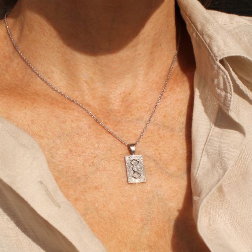 fig 2. A rectangular Art Deco pendant set with a central round old cut diamond within a geometric diamond-paved frame on a silver chain.
