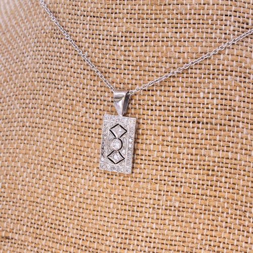 fig 3. A rectangular Art Deco pendant set with a central round old cut diamond within a geometric diamond-paved frame on a silver chain.