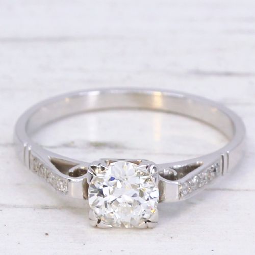 fig 2. A vintage white metal engagement ring set with a central round old cut diamond flanked by small shoulder diamonds.