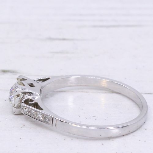 fig 3. A vintage white metal engagement ring set with a central round old cut diamond flanked by small shoulder diamonds.