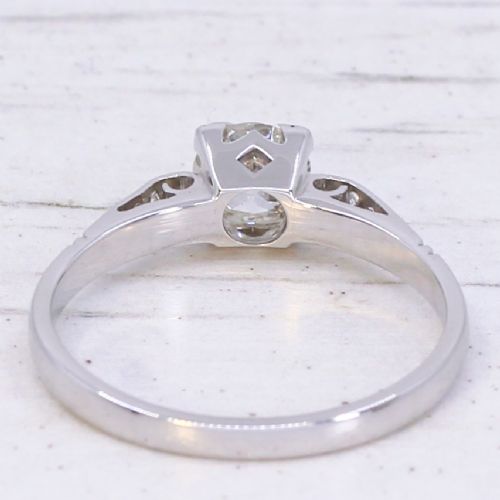 A vintage white metal engagement ring set with a central round old cut diamond flanked by small shoulder diamonds. View V