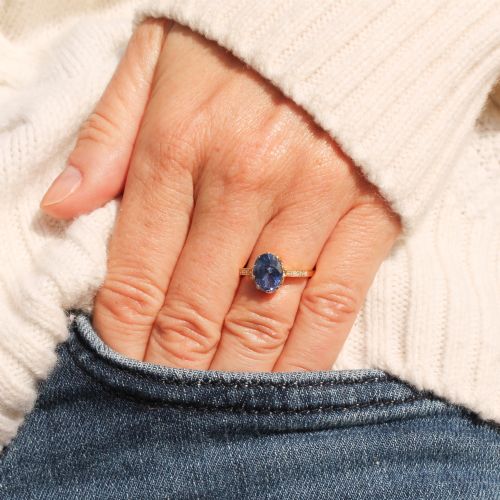 fig 1. A vintage yellow gold ring featuring an oval-cut blue sapphire in a claw setting with diamond-set shoulders.