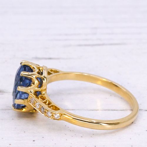 fig 3. A vintage yellow gold ring featuring an oval-cut blue sapphire in a claw setting with diamond-set shoulders.