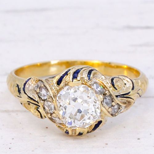 fig 2. A Victorian yellow gold solitaire ring featuring a central old cut diamond surrounded by blue enamel scrollwork and accent diamonds.
