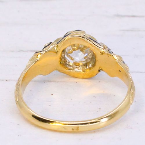 fig 4. A Victorian yellow gold solitaire ring featuring a central old cut diamond surrounded by blue enamel scrollwork and accent diamonds.