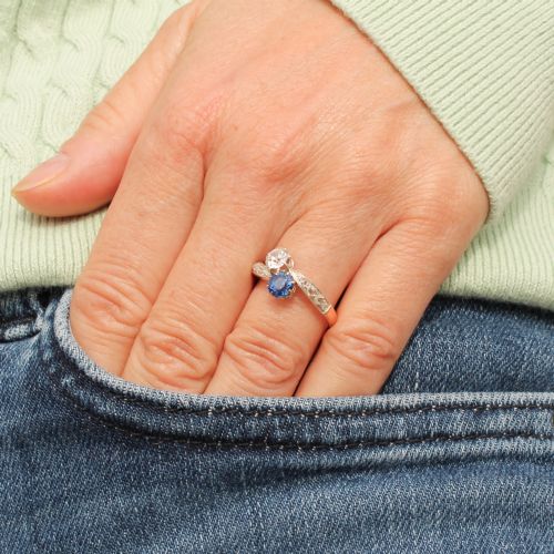 fig 1. An antique Edwardian gold and platinum crossover ring set with a round blue sapphire and a diamond in a Moi et Toi design.