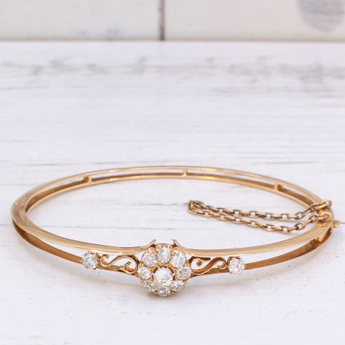 fig 3. A late Victorian yellow gold hinged bangle featuring a central old-cut diamond cluster flanked by scrollwork and accent diamonds.
