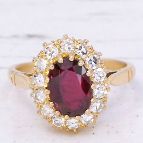 fig 2. A vintage yellow gold ring featuring a central oval-cut red ruby framed by a halo of brilliant round diamonds.