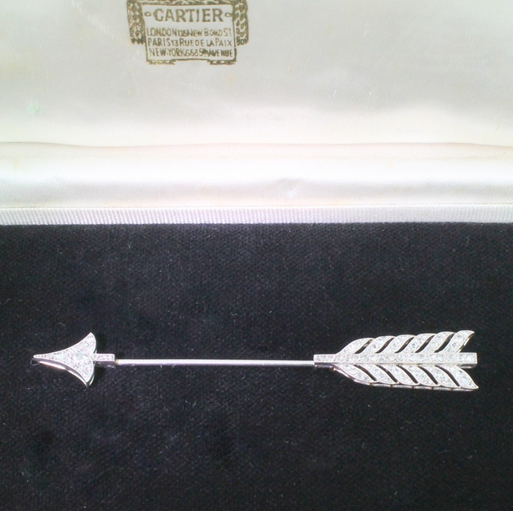 An antique diamond and platinum arrow jabot pin displayed inside a fitted presentation case.