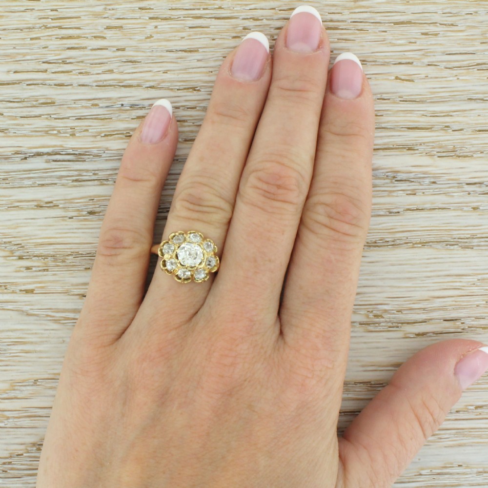 A Victorian yellow gold ring featuring a central old cut diamond surrounded by a halo of smaller diamonds in a scalloped cluster setting. View VI