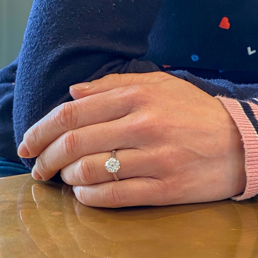 An Art Deco solitaire ring featuring a round old cut diamond held in a six-prong setting with tapered geometric shoulders crafted in white metal. View VIII