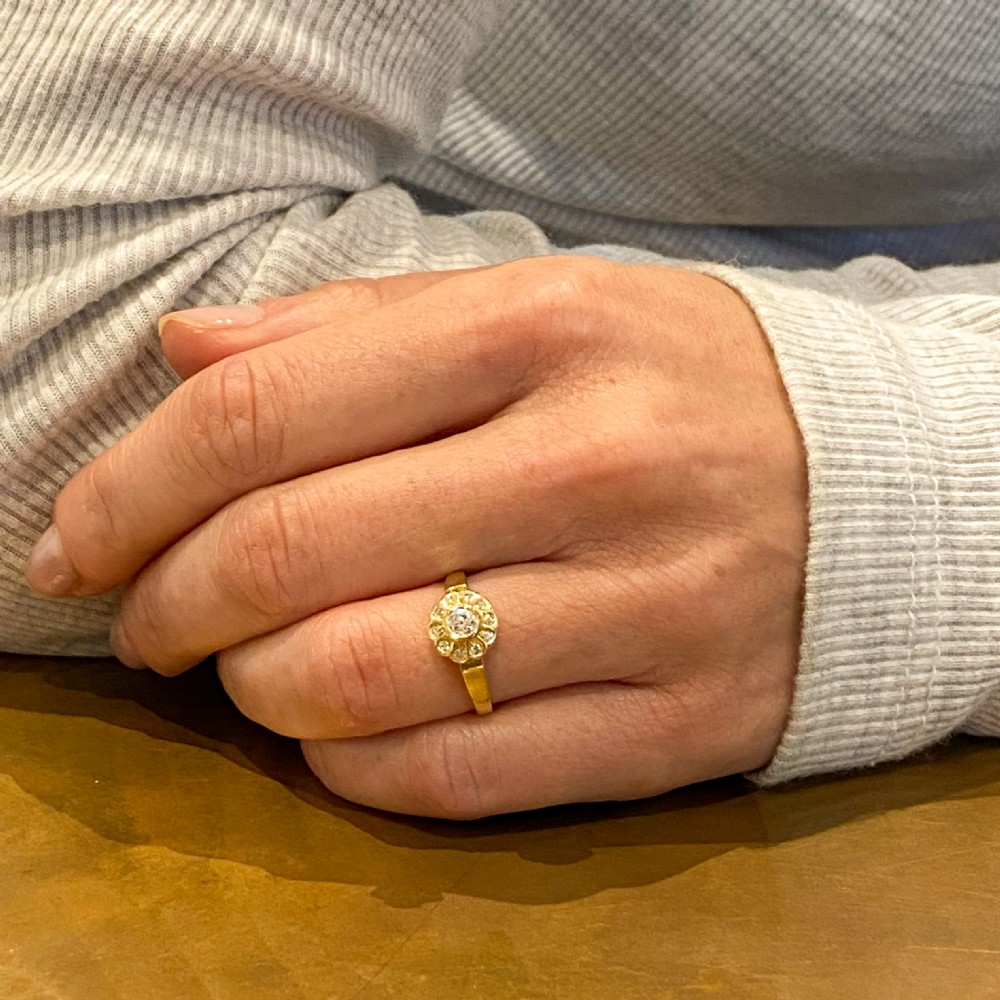 An Edwardian yellow gold cluster ring featuring a central old cut diamond surrounded by smaller diamonds in a scalloped setting. View VII