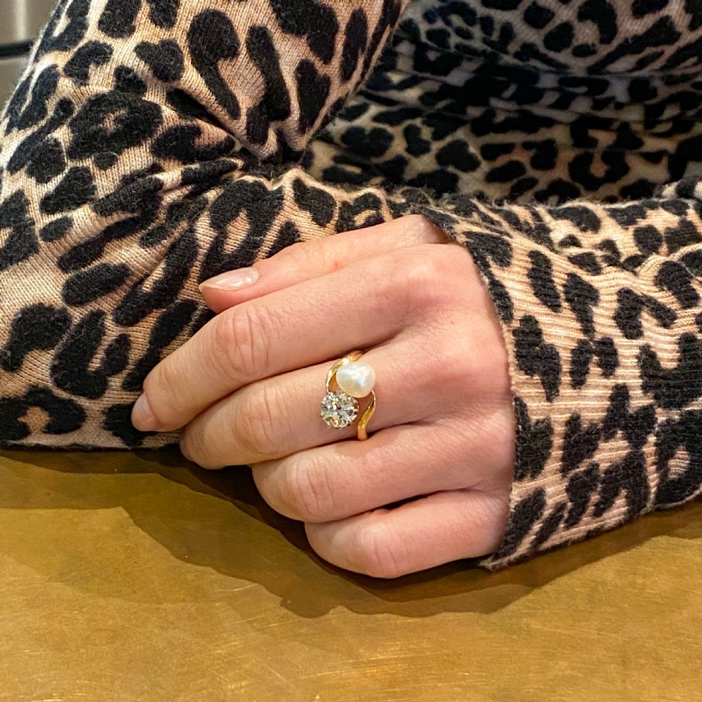 An Edwardian yellow gold crossover ring set with a natural white pearl and a round old cut diamond on a curved band. View VIII