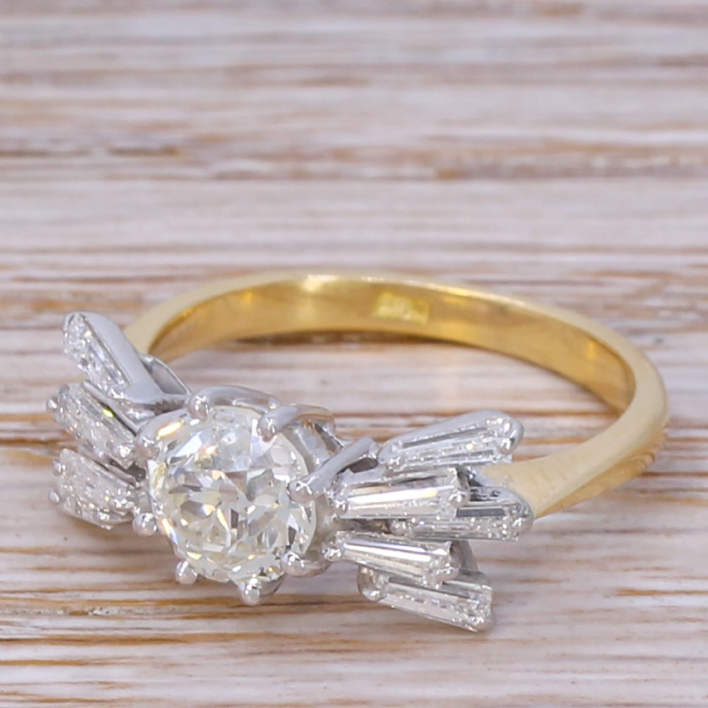 A Mid-Century diamond ring featuring a central round old-cut diamond flanked by fanned tapered baguette cut diamonds on a yellow gold band.