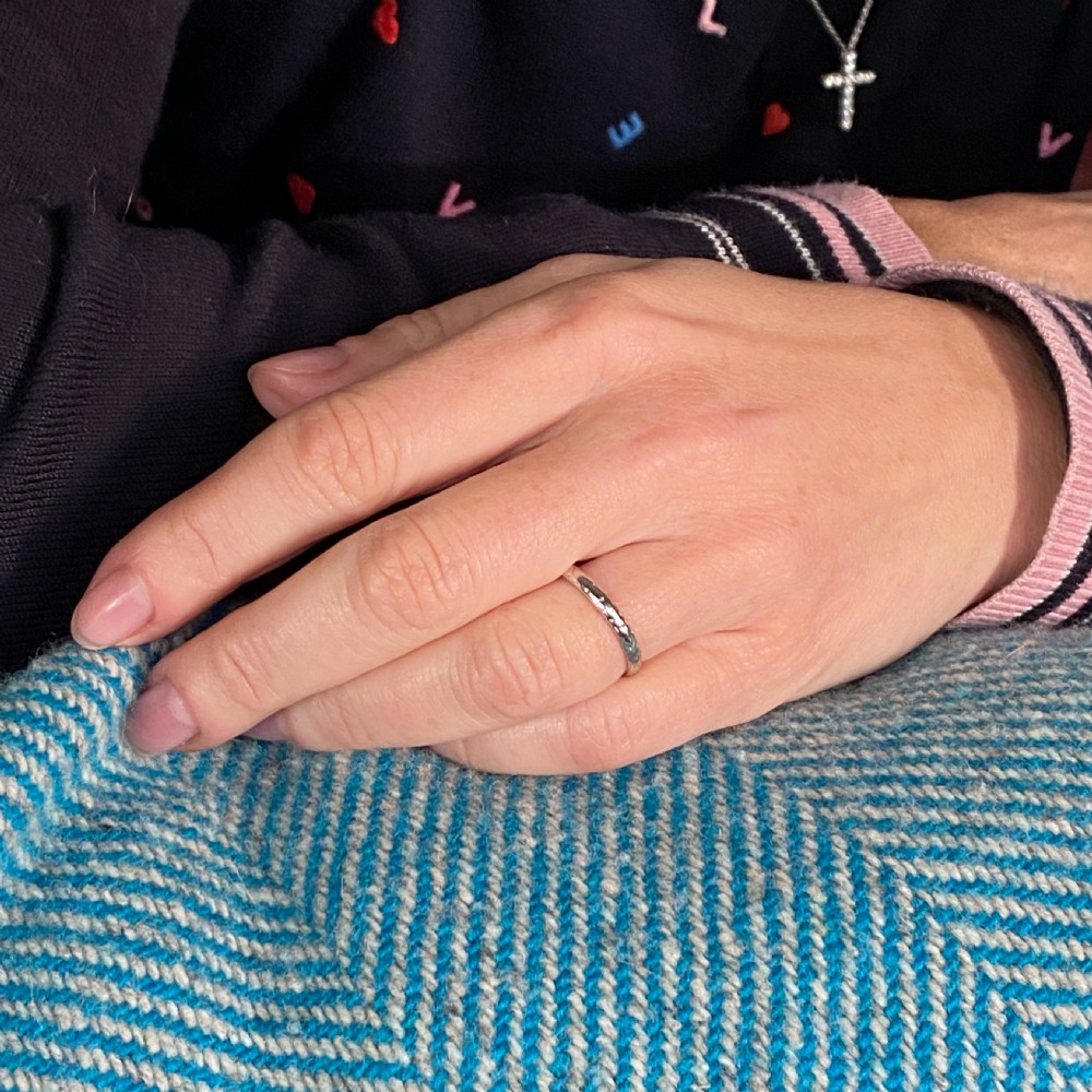 A slim platinum Art Deco wedding ring featuring engraved detailed patterns around the exterior band and an internal stamp. View IV