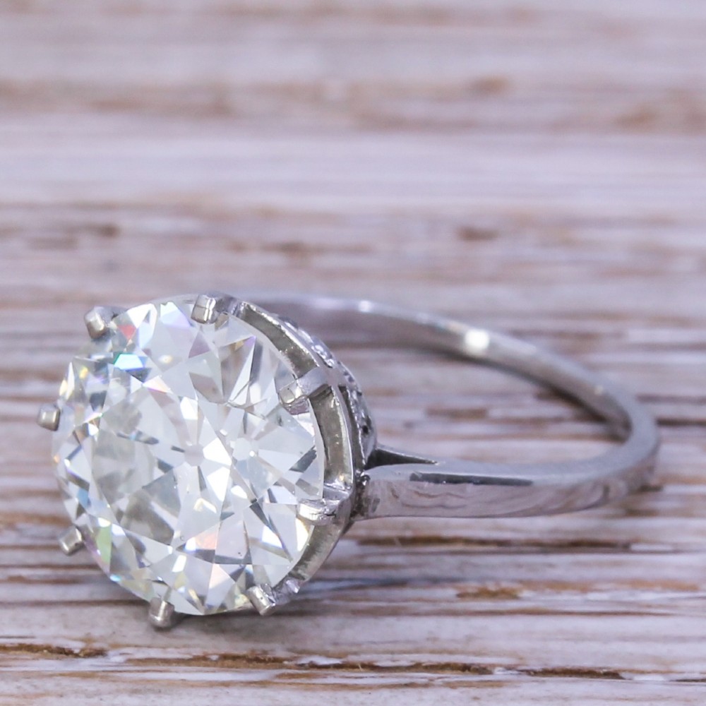 An Art Deco diamond solitaire ring featuring a large round Old European cut diamond held in a multi-prong setting on a smooth metal band.