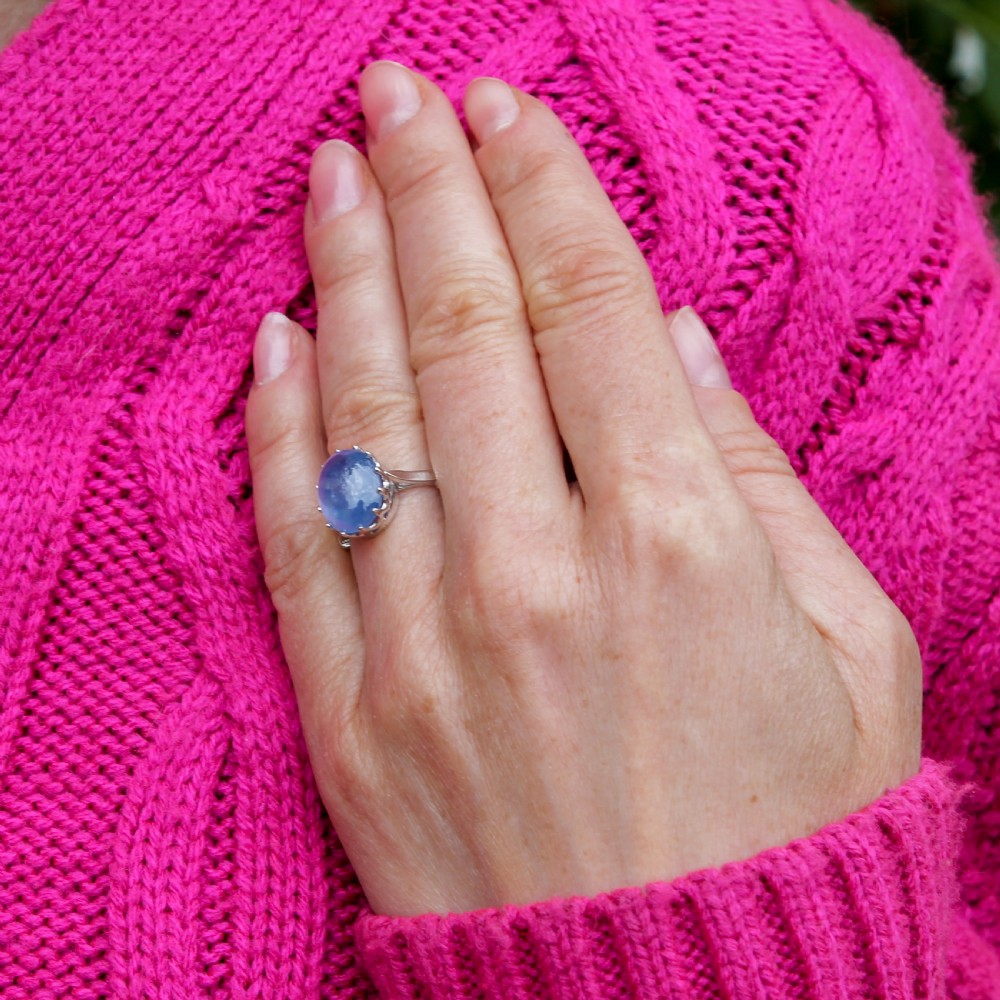 An Art Deco platinum ring featuring a large oval blue cabochon sapphire held in a multi-claw setting. View VIII