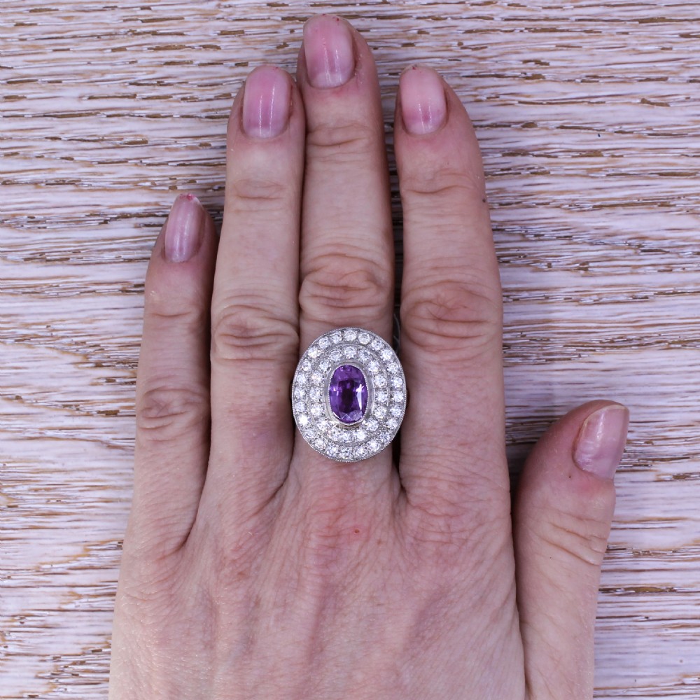 An oval purple sapphire mounted within a double halo of brilliant-cut diamonds on a platinum ring band. View VII