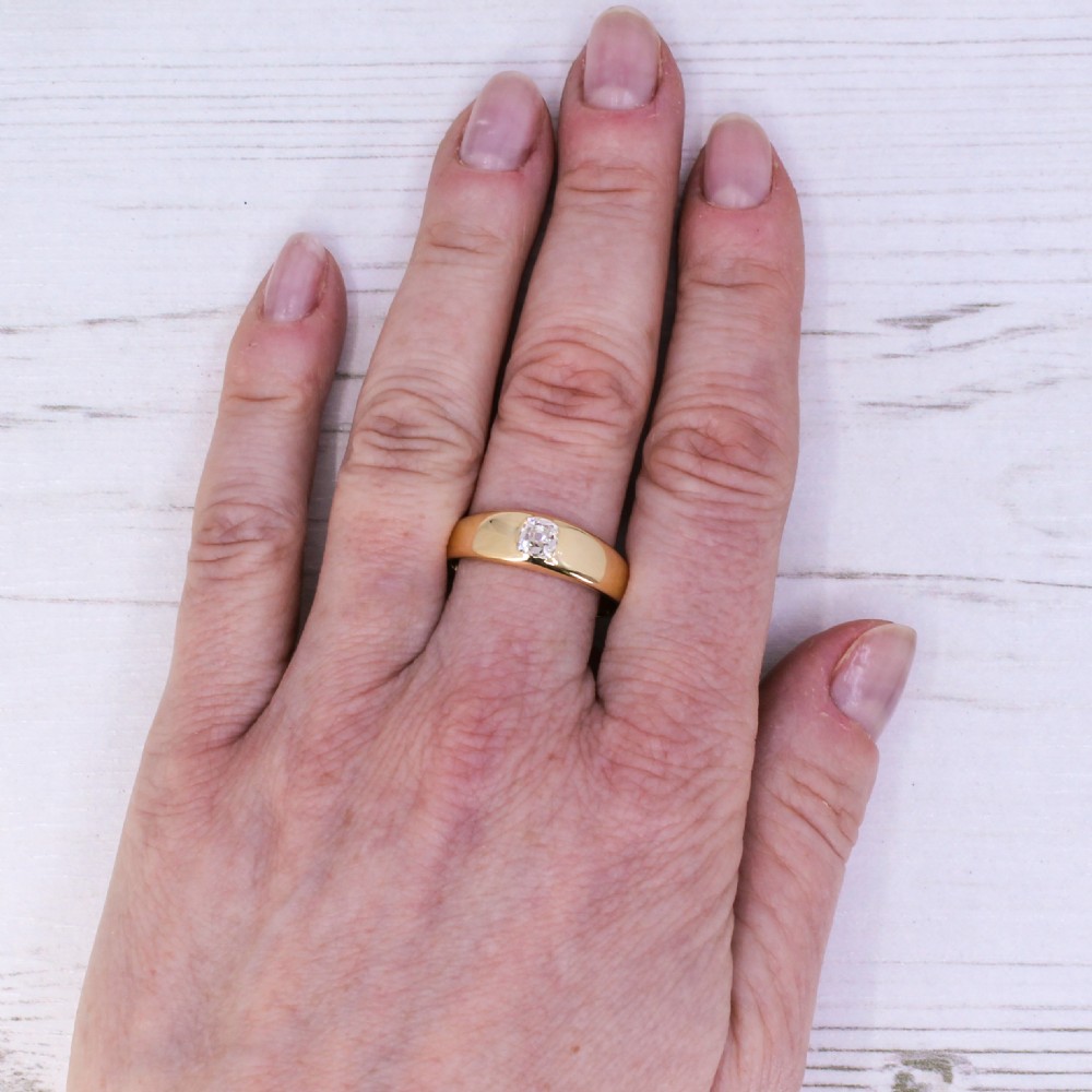 A smooth yellow gold band ring featuring a single flush-set old cut diamond at its centre. View VII