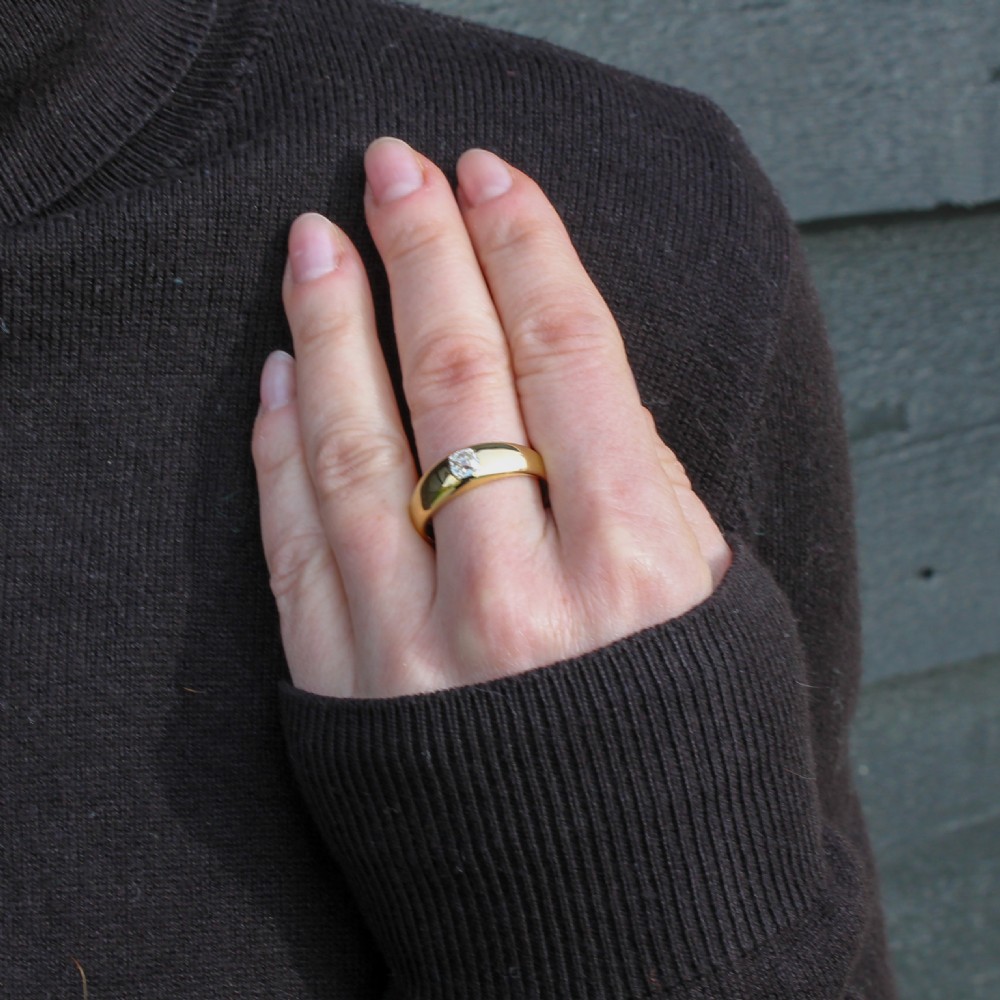 A smooth yellow gold band ring featuring a single flush-set old cut diamond at its centre. View IX