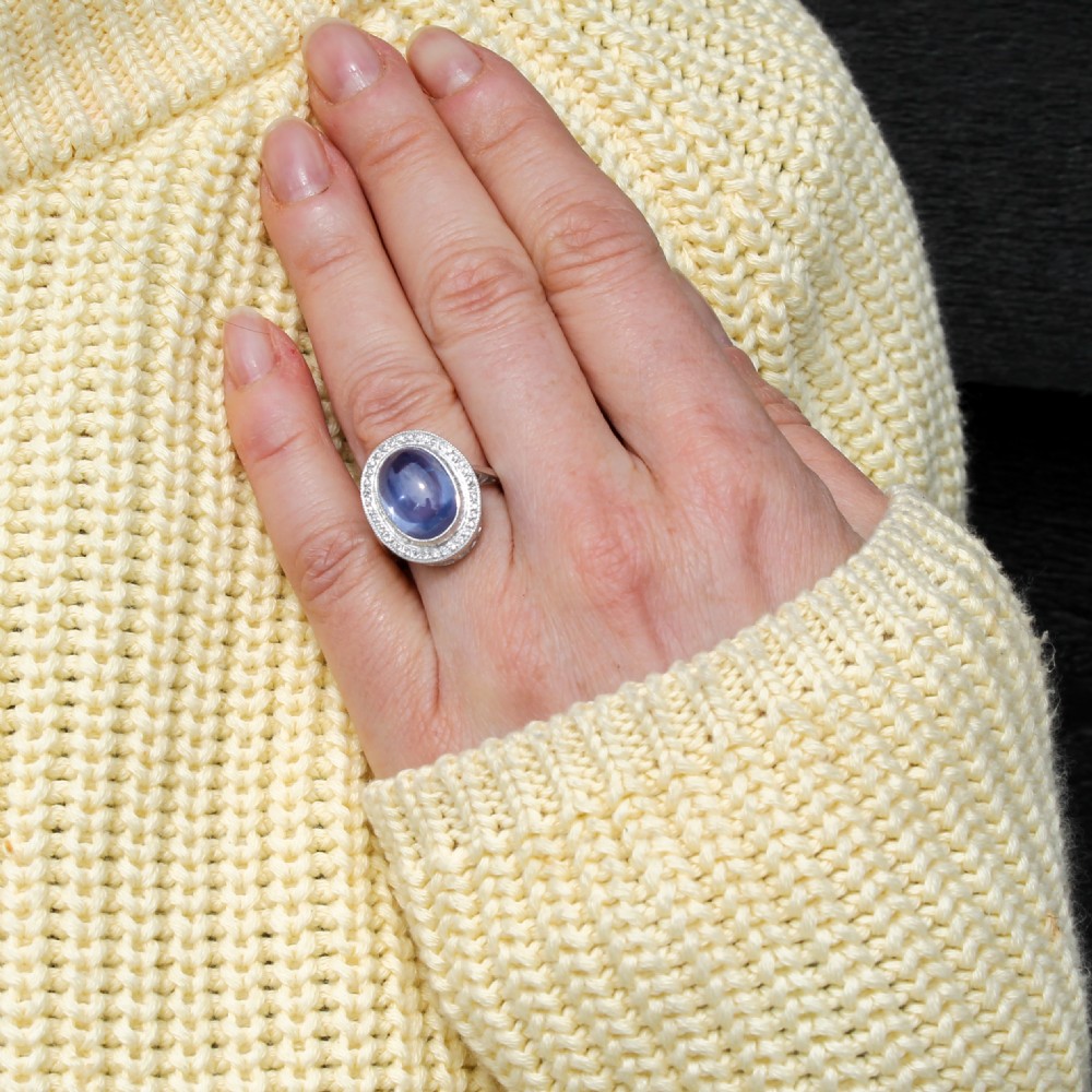 An Art Deco ring featuring a large oval cabochon blue sapphire surrounded by a platinum frame set with small diamonds. View II