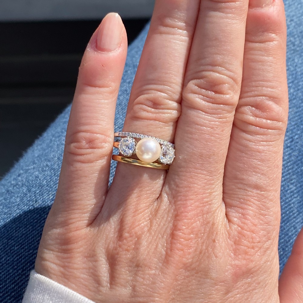 An Art Deco trilogy ring featuring a central white pearl flanked by two old cut diamonds on a gold shank. View IX