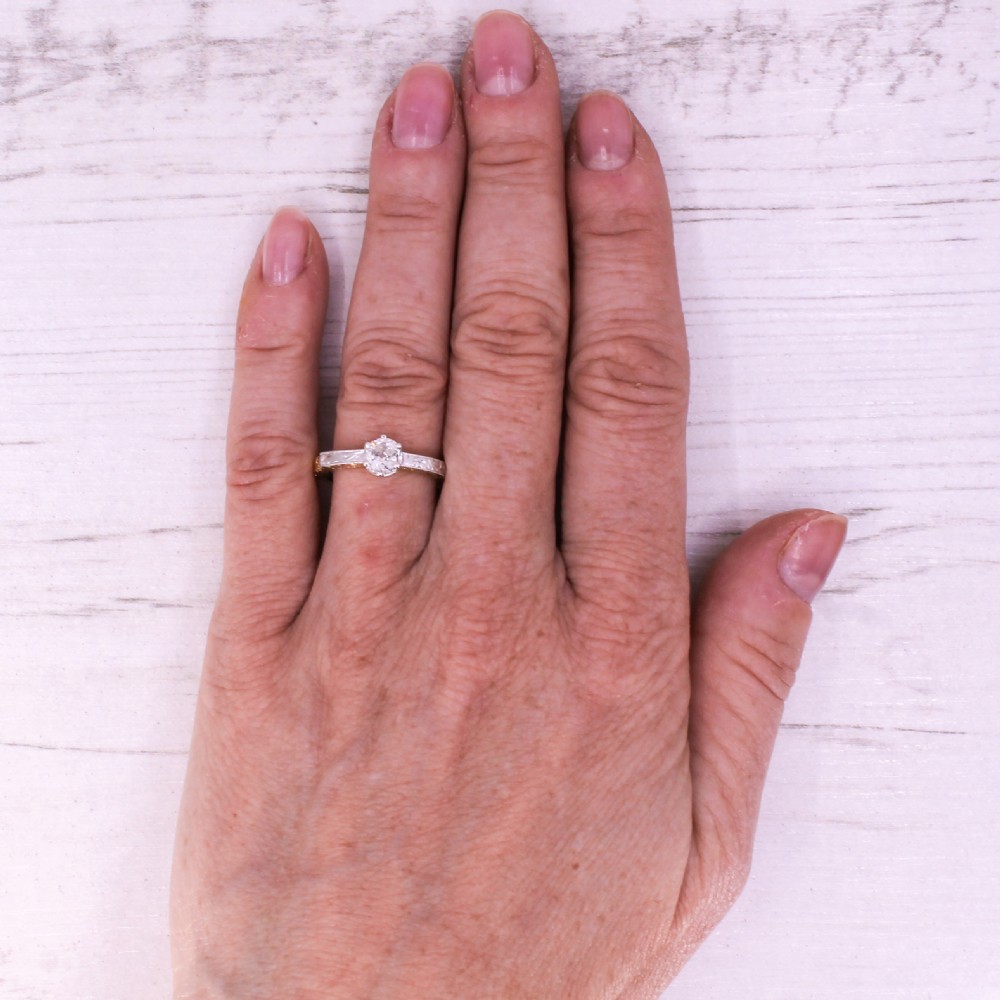 An Edwardian yellow gold and platinum solitaire ring featuring a central old cut diamond set between hand-engraved scrollwork shoulders. View VII
