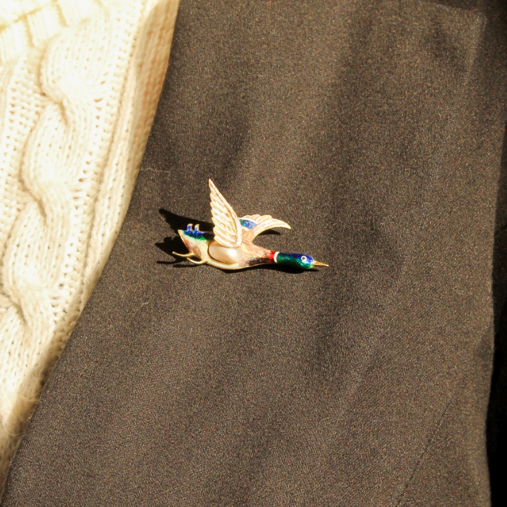 A late Victorian gold brooch shaped as a mallard duck in flight with colourful vitreous enamel and a pearl body. View VI