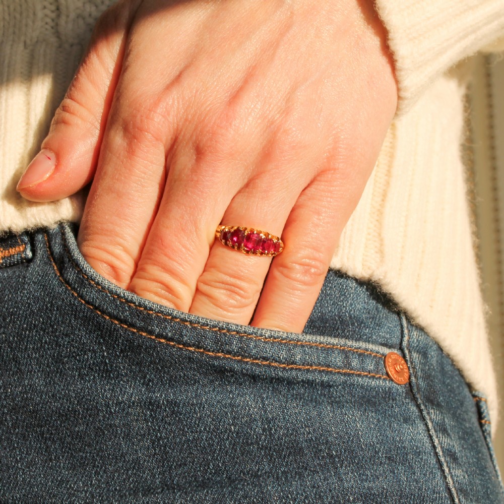 A Victorian yellow gold ring set with five graduated cushion-cut red rubies in a carved claw setting. View VII