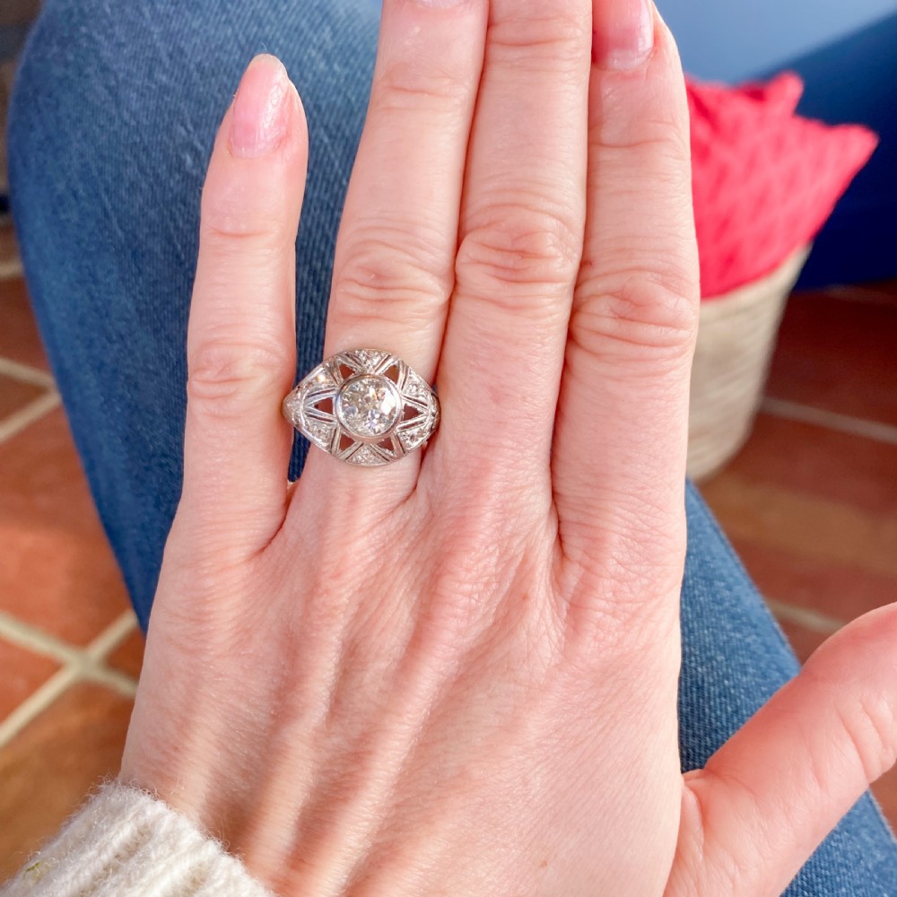An Art Deco platinum ring featuring a central old cut diamond set within a domed openwork star motif bordered by millegrain detailing. View VI