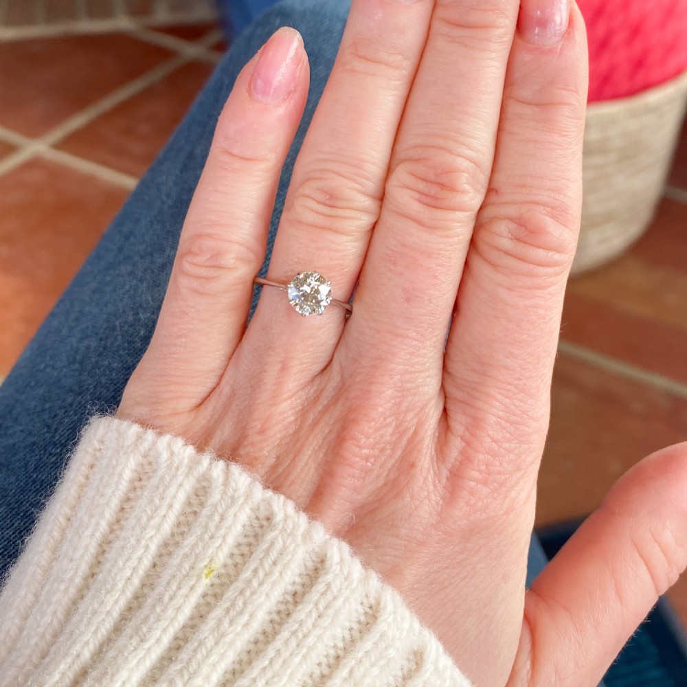 A mid-century platinum engagement ring featuring a central round transitional cut diamond secured in a multi-claw setting on a slender band. View VII