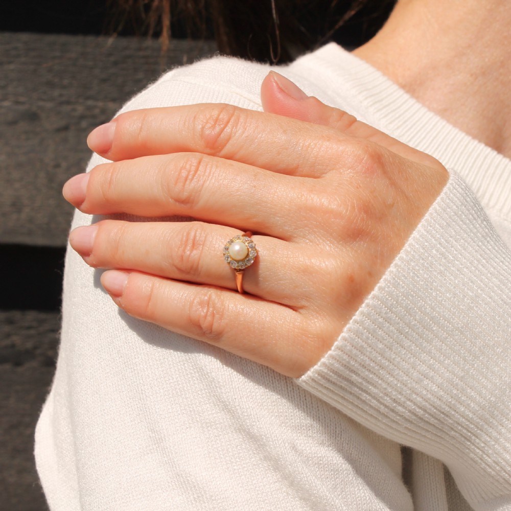 An Art Deco gold ring featuring a central white pearl surrounded by a circular halo of old cut diamonds. View VI