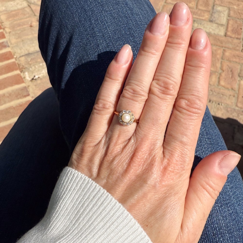 An Art Deco gold ring featuring a central white pearl surrounded by a circular halo of old cut diamonds. View VII