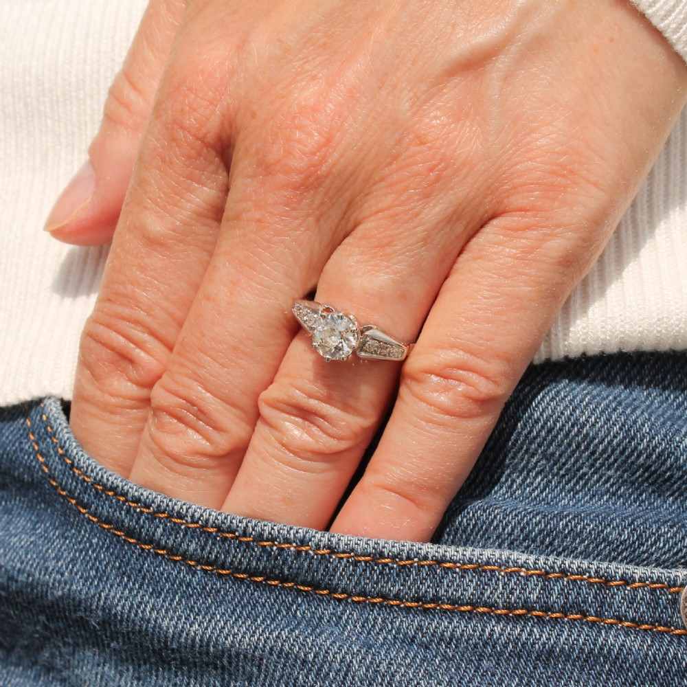 An Art Deco diamond engagement ring featuring a central round old European cut diamond set in platinum with geometric, diamond-paved shoulders and millegrain detailing. View II