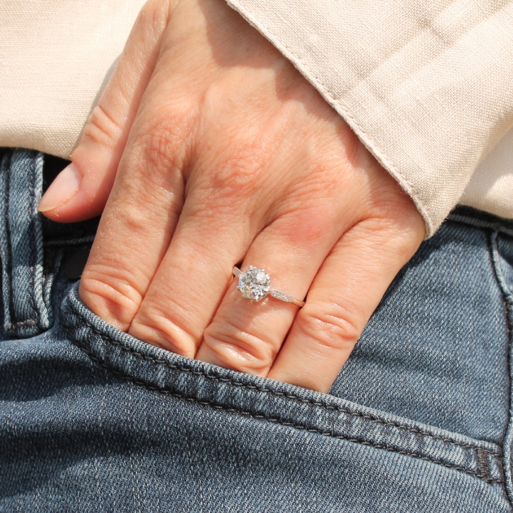 A mid-century platinum engagement ring featuring a central round old-cut diamond in a multi-claw setting with milgrain diamond shoulders. View II