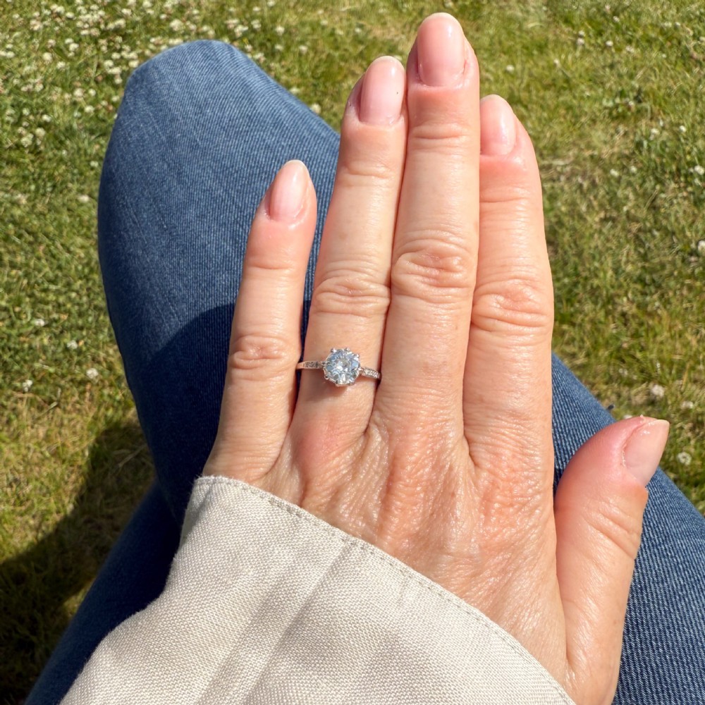 A mid-century platinum engagement ring featuring a central round old-cut diamond in a multi-claw setting with milgrain diamond shoulders. View VII