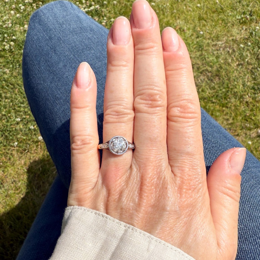 A mid-century engagement ring featuring a central old cut diamond set in a white metal bezel head with accent shoulders on a gold band. View VI