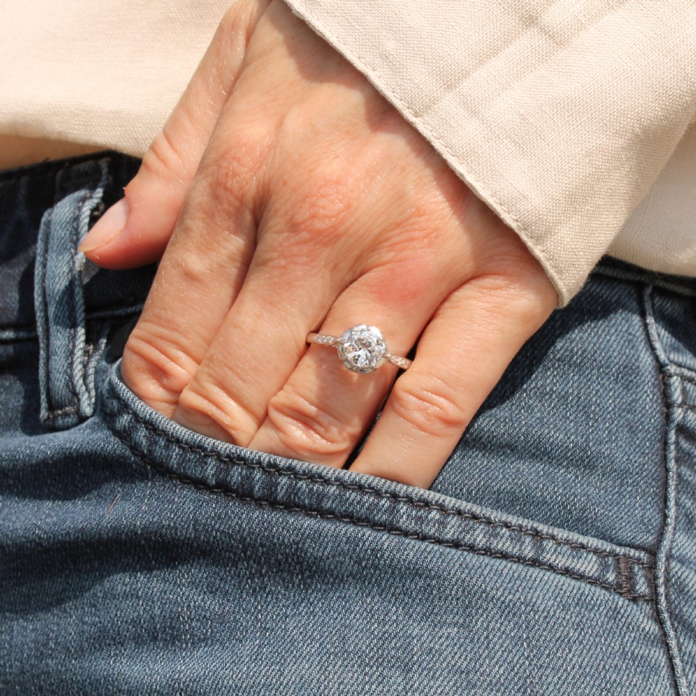 An Art Deco solitaire engagement ring featuring a central round old cut diamond set in white metal with accent diamonds set into the shoulders. View II