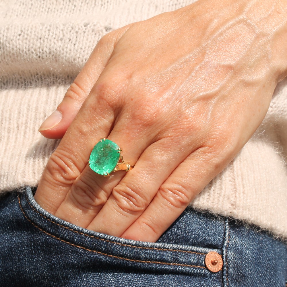 A mid-century yellow gold solitaire ring featuring a large cushion-cut green emerald secured with double claw settings. View VII