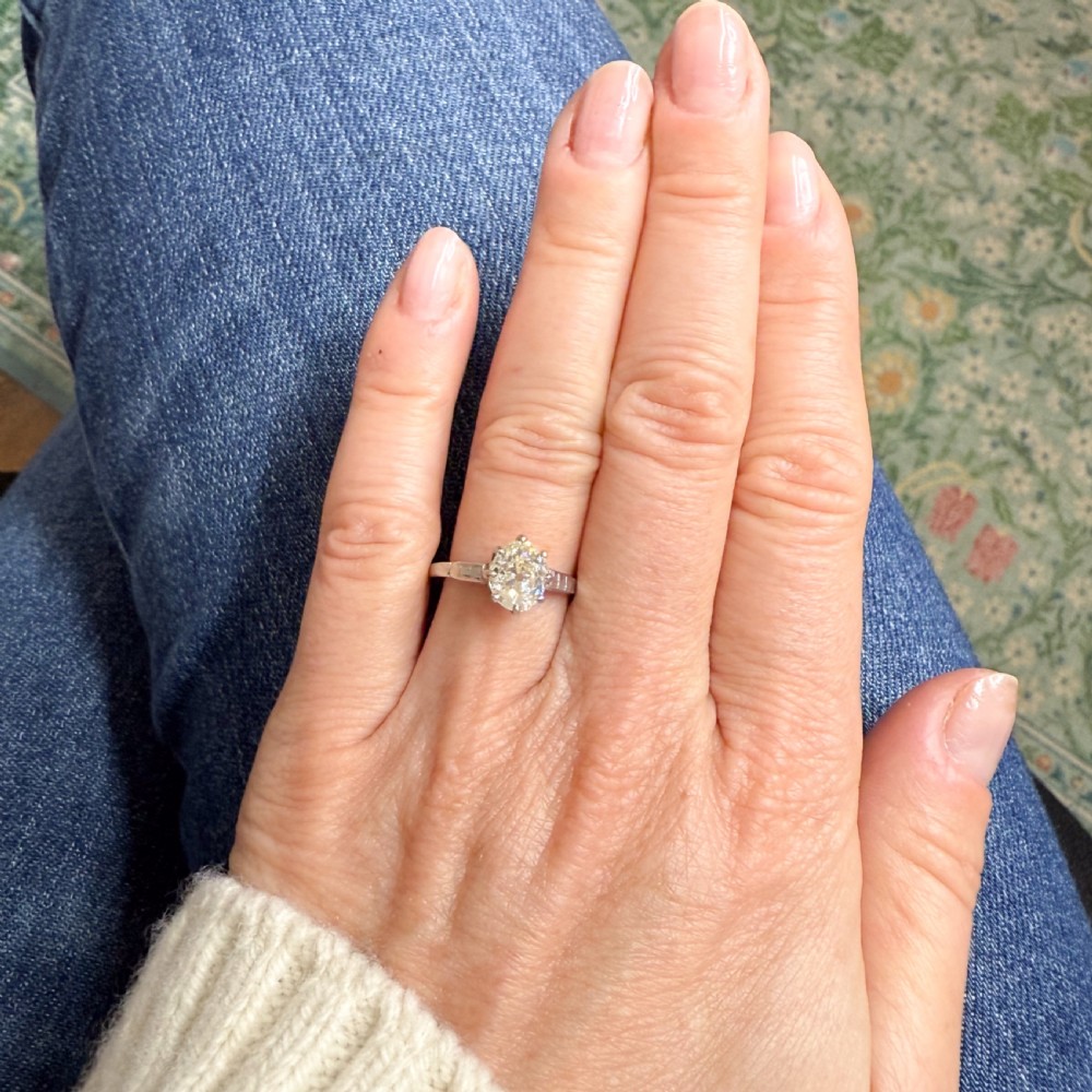 An Art Deco diamond ring featuring an old oval cut diamond set in a silver-toned band with stepped shoulders. View VII