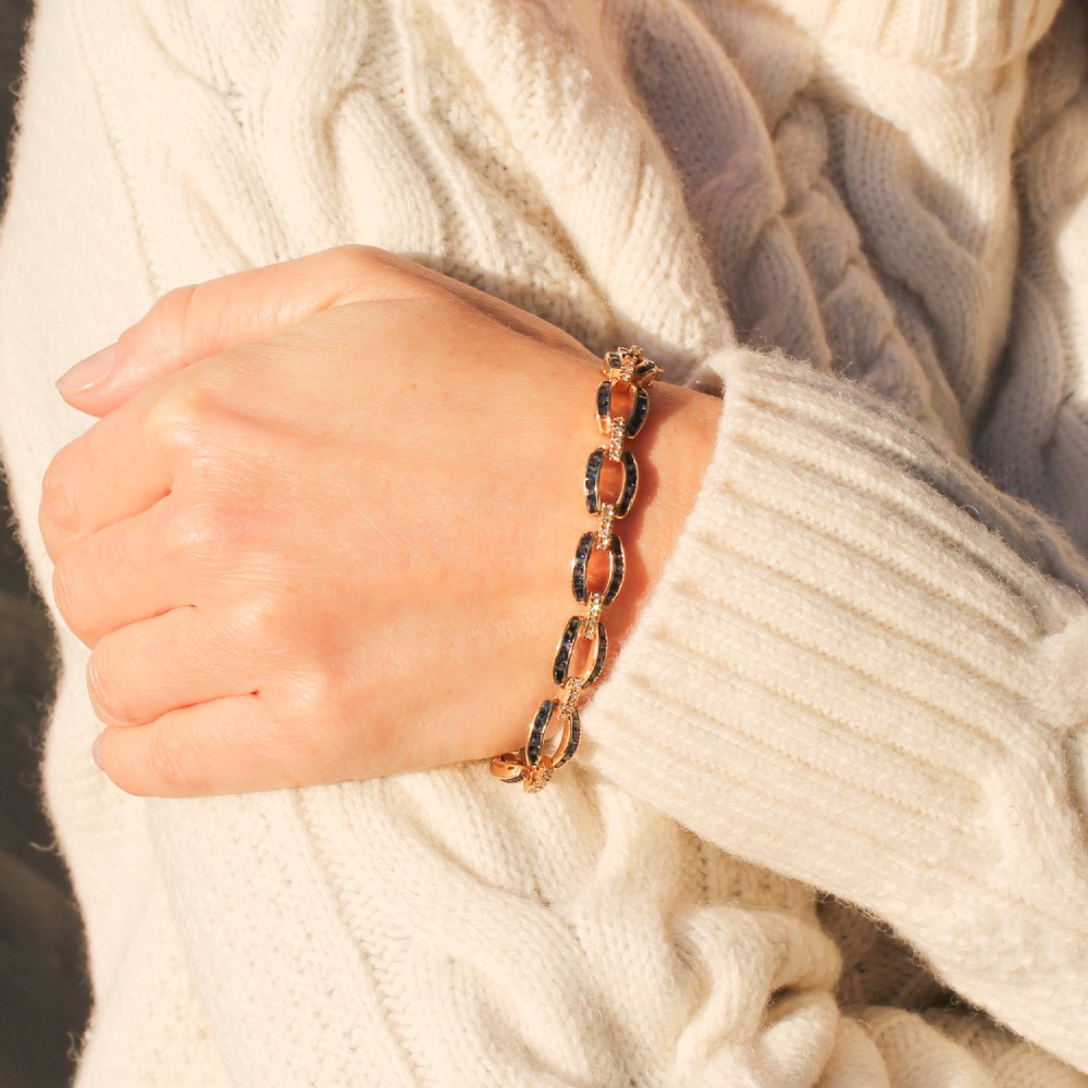 A yellow gold link bracelet set with channel-set blue sapphires and accented with small diamonds between each link. View VIII