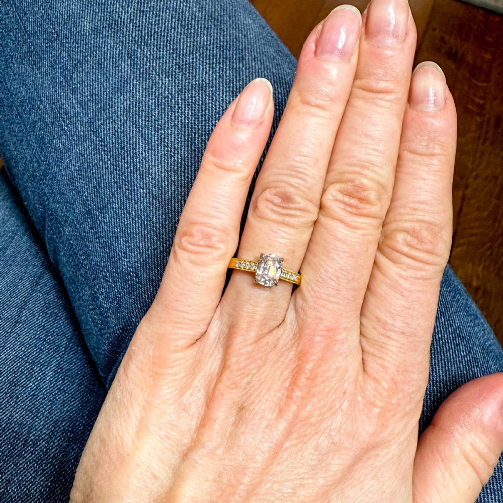 A yellow gold ring set with a cushion-shaped old mine cut diamond in platinum claws and accent diamonds along the shoulders. View VII
