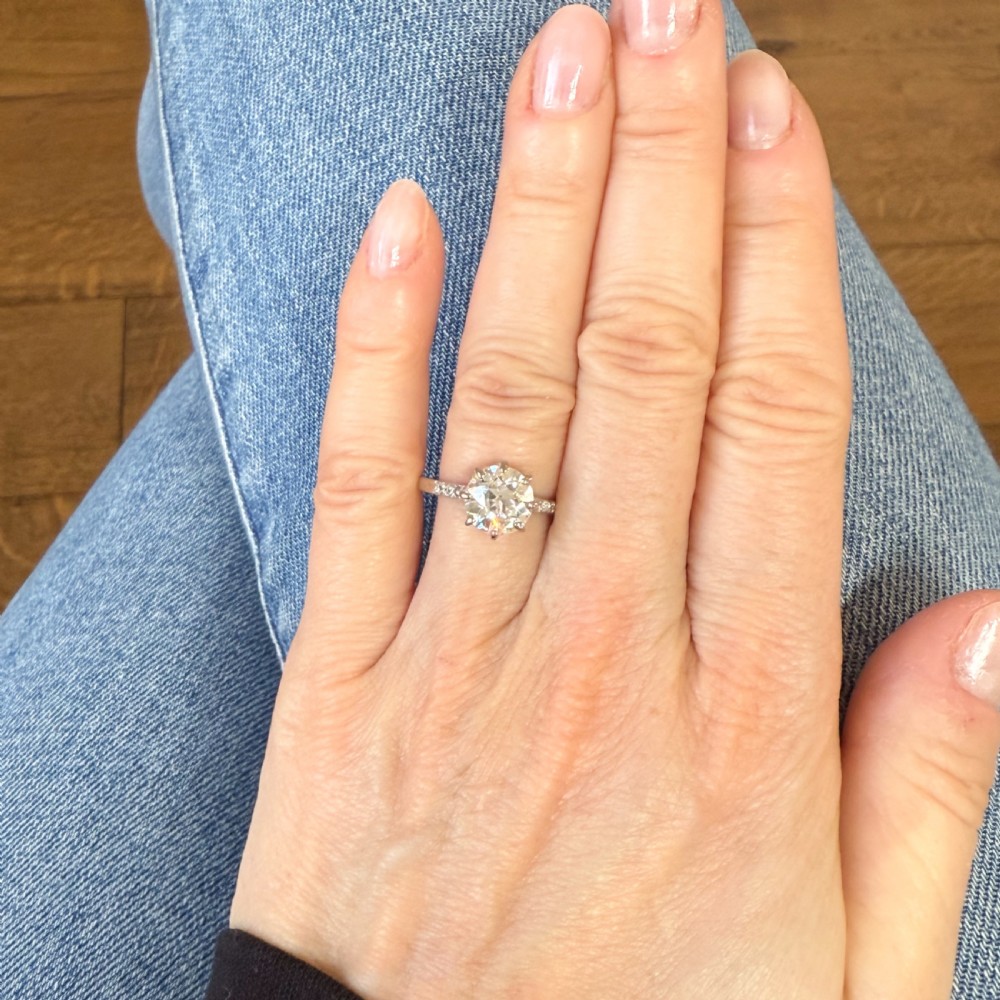 A vintage platinum engagement ring featuring a central round old cut diamond held in an eight-claw setting with small accent diamonds along the shoulders. View VII
