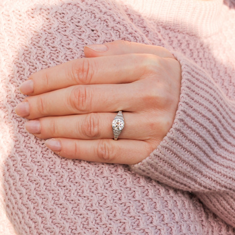 An Art Deco diamond ring featuring a central round old cut diamond set in platinum with small diamond accents along geometric shoulders. View II