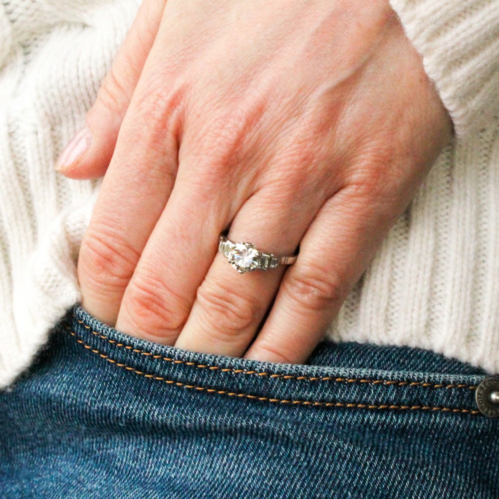 A platinum ring featuring a central round transitional cut diamond with baguette diamond shoulders. View VII